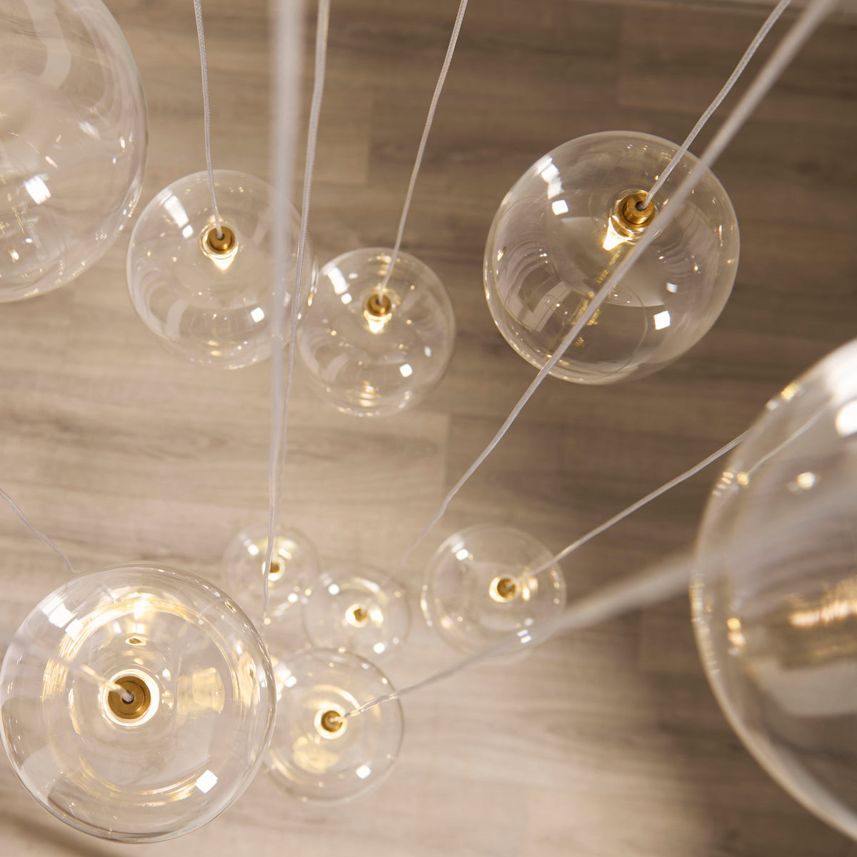 Oslo cascade pendant seen from above showing clear glass globes spiralling over a wood floor