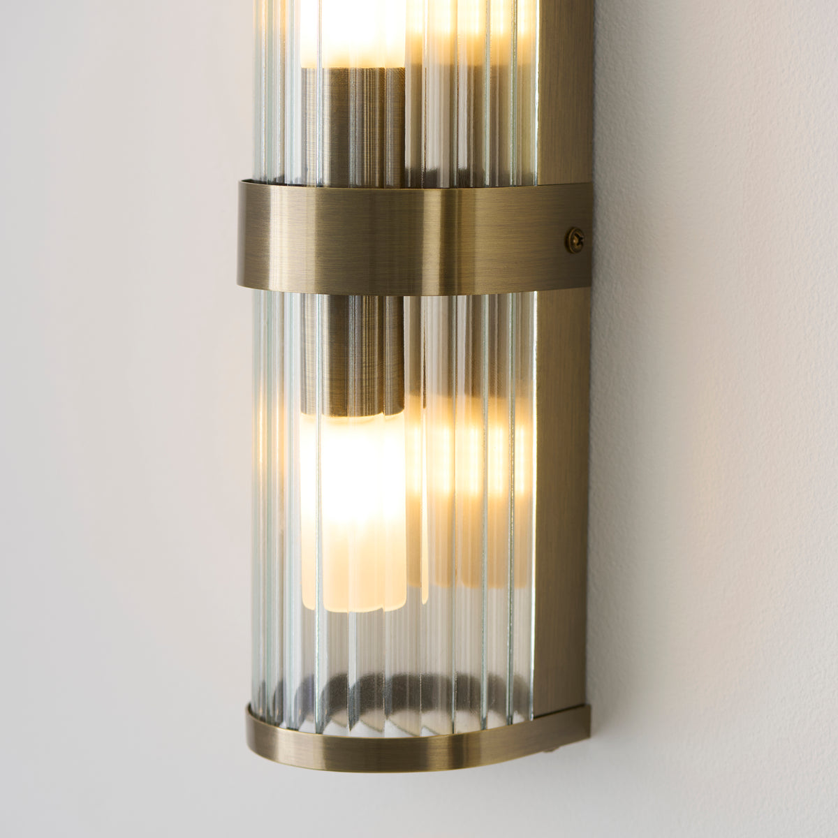 Close-up of the Ridgeton wall light's brass central band and lower ribbed glass shade