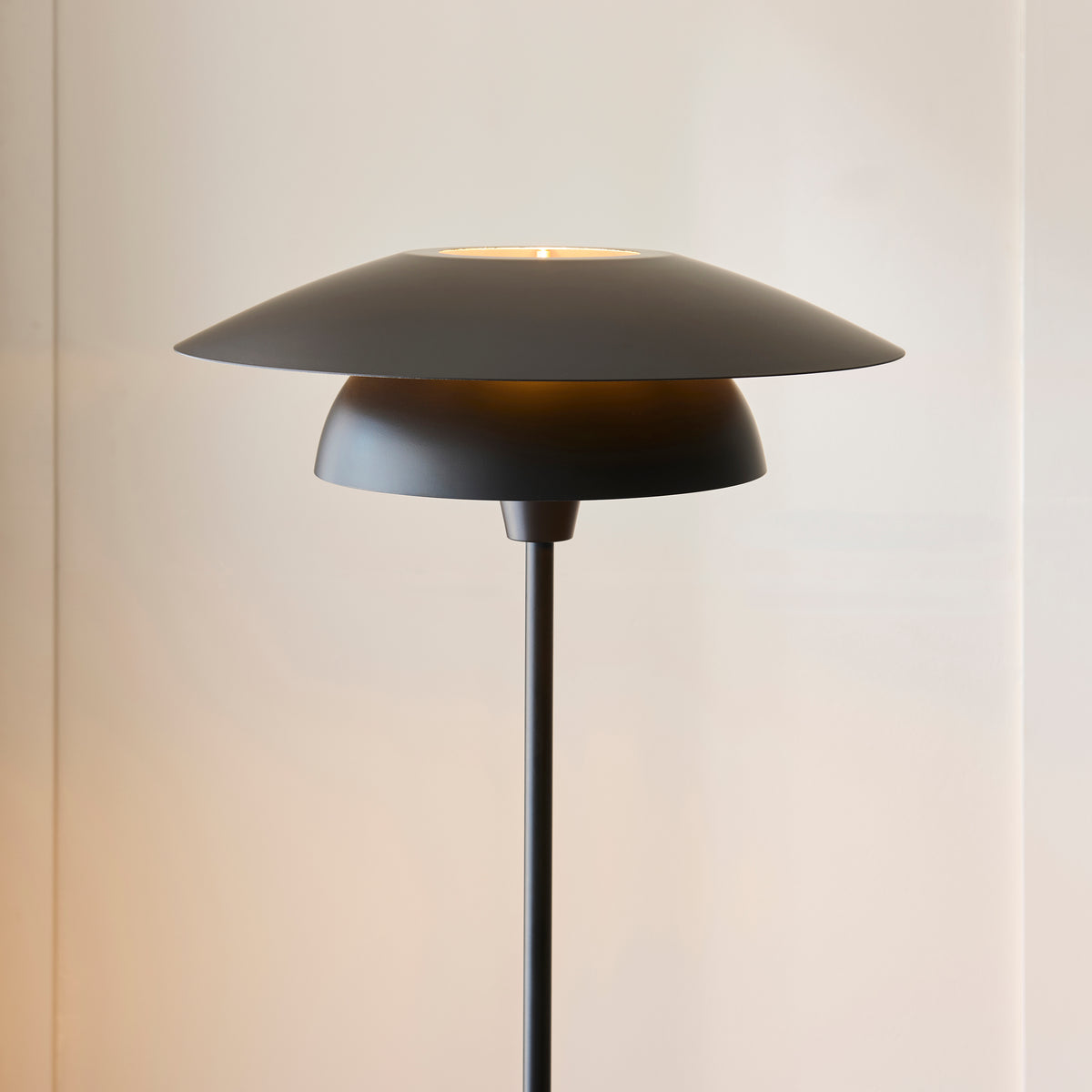 Close-up of the Lyon floor lamp's tiered matt black shades with warm light beneath