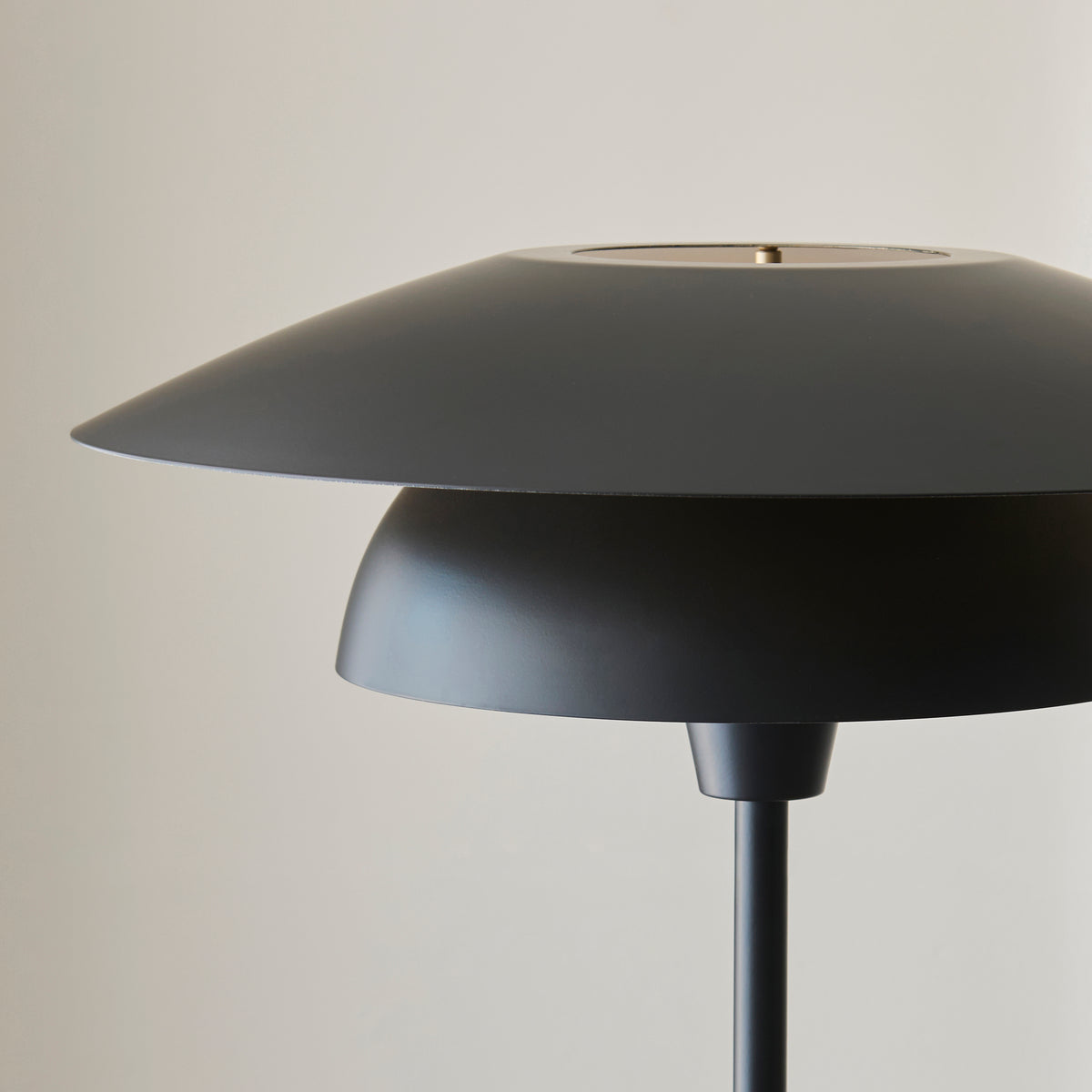 Layered matt black discs of the Lyon floor lamp shade seen against a pale wall