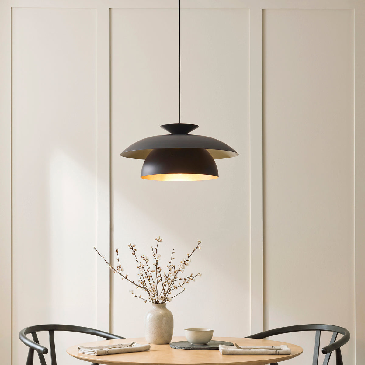 Lyon layered pendant lit above a dining table set with a stoneware vase and bowl