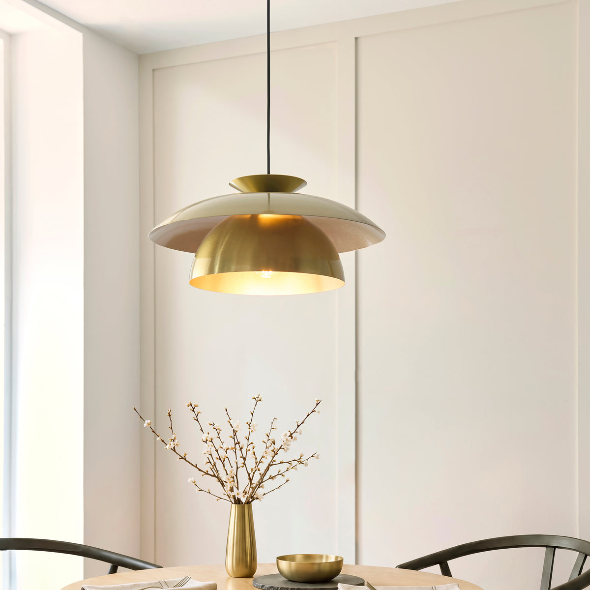 Lyon satin brass pendant casting warm light over an oak dining table in a panelled room