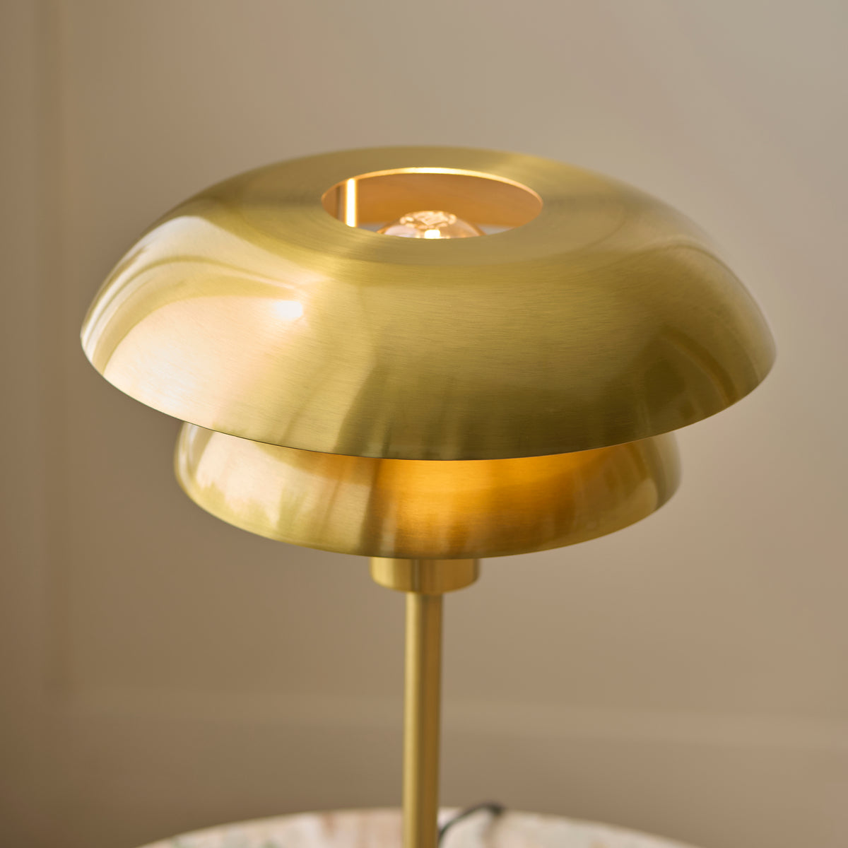 Close-up of the Lyon table lamp's brushed brass tiered shades and lit centre