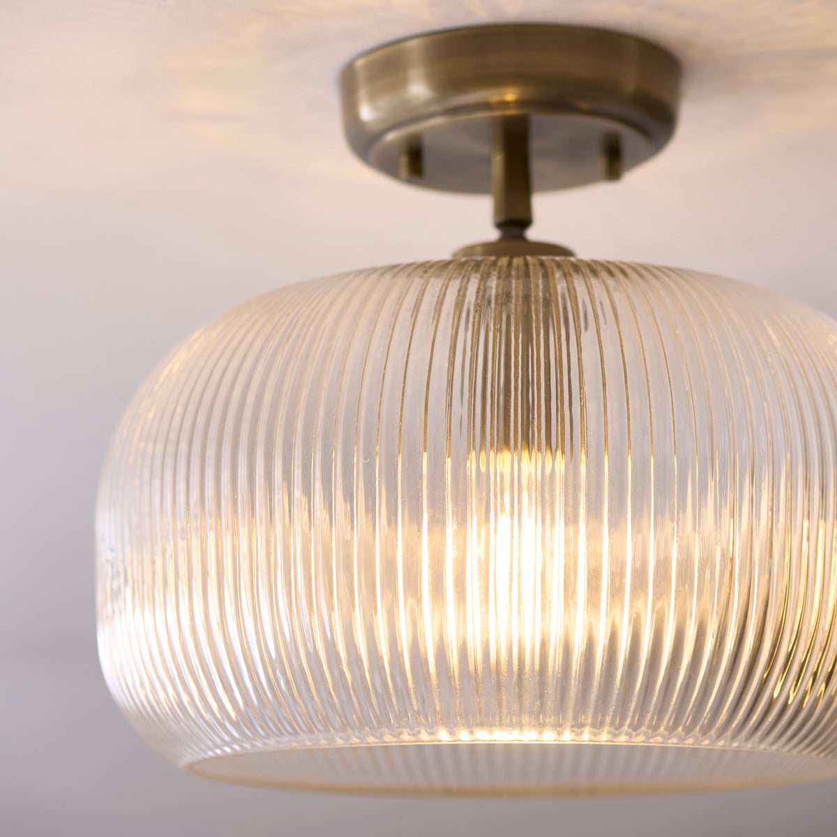 Angled close-up of the Harborne light's fluted glass shade and lit filament lamp