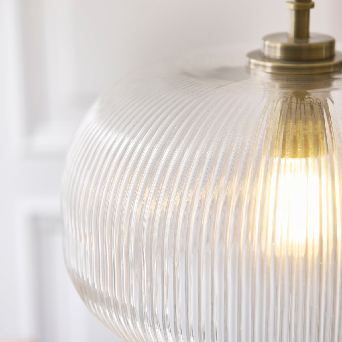 Close-up of ribbed clear glass on the Harborne pendant with warm bulb light behind the fluted surface