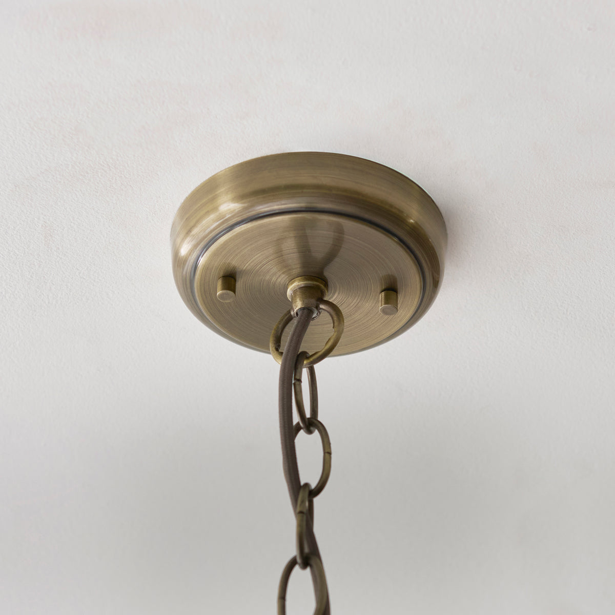Antique brass ceiling rose and chain link of the Harborne pendant light against a white ceiling