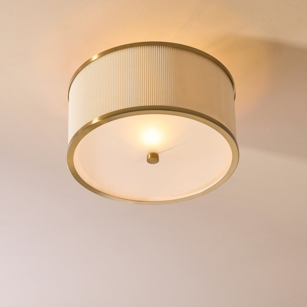 Lexi brass and ivory flush ceiling light glowing softly against a plain painted ceiling