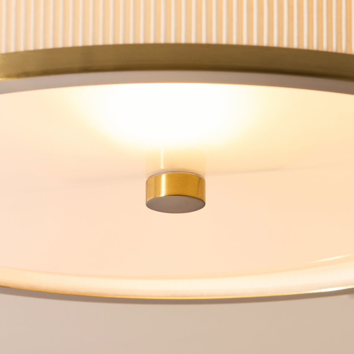 Detail of the frosted glass diffuser and brass finial beneath the lit Lexi flush ceiling light