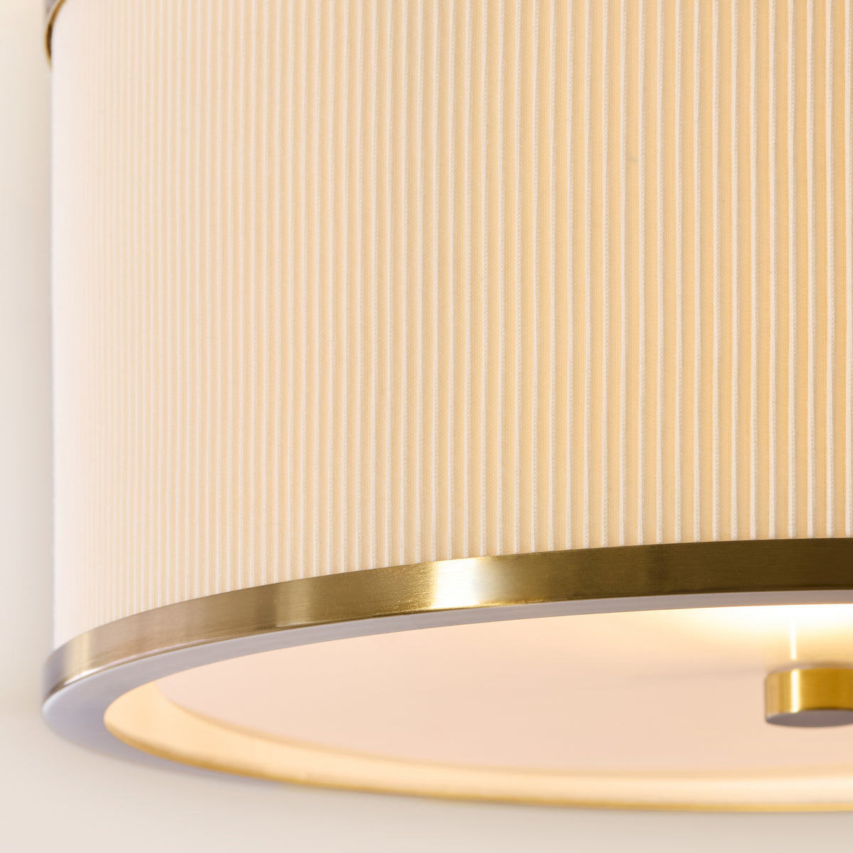 Close view of the ivory pleated fabric and brushed brass banding on the Lexi flush ceiling light