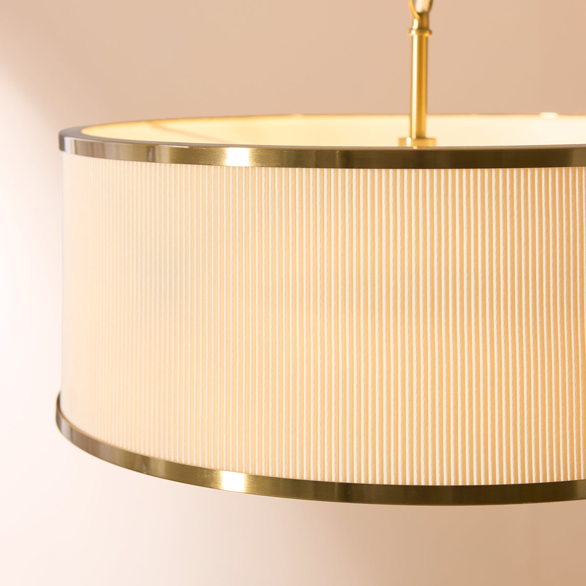 Close-up of the pleated ivory shade and aged brass trim on the lit Lexi pendant light