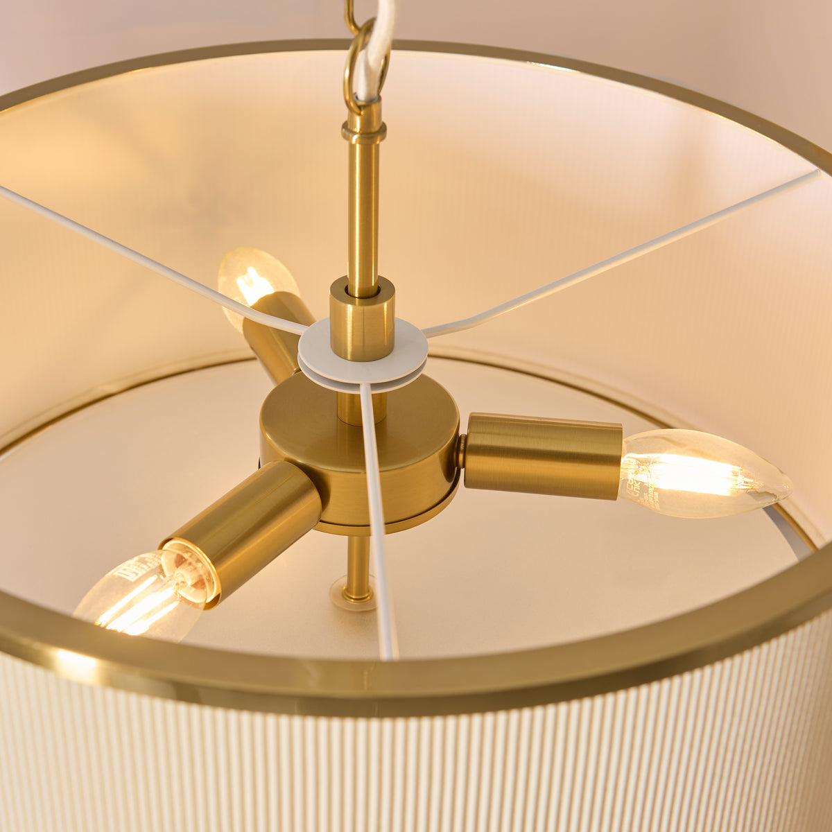 Three brass lamp holders with candle bulbs inside the ivory Lexi pendant shade