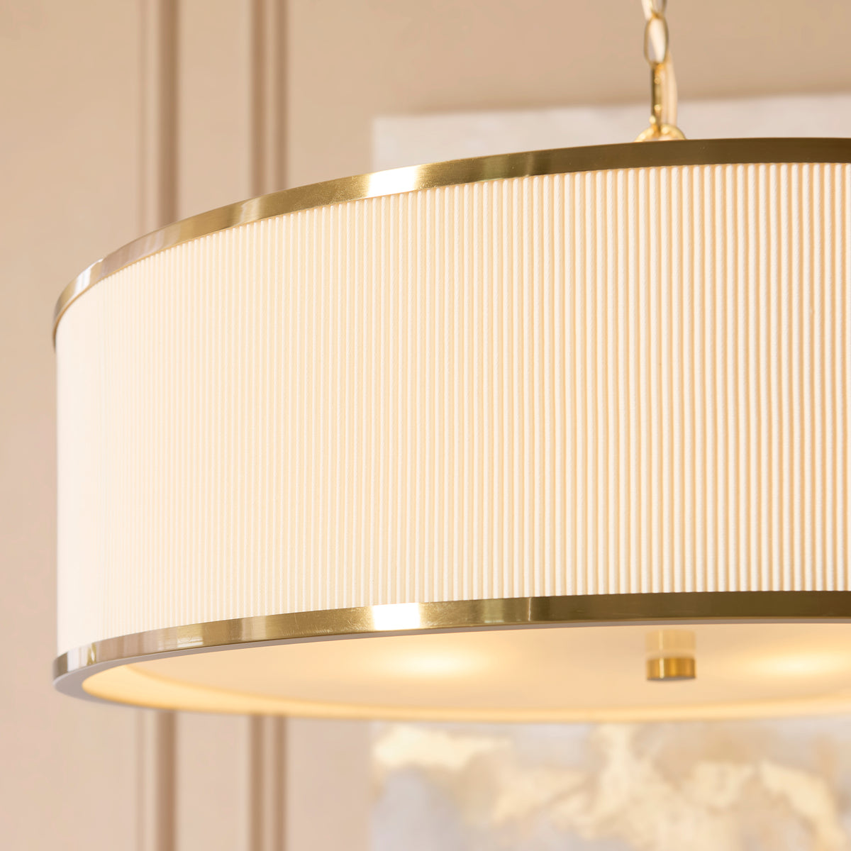 Close view of the lit Lexi pendant showing ivory pleated fabric, brass banding and diffuser