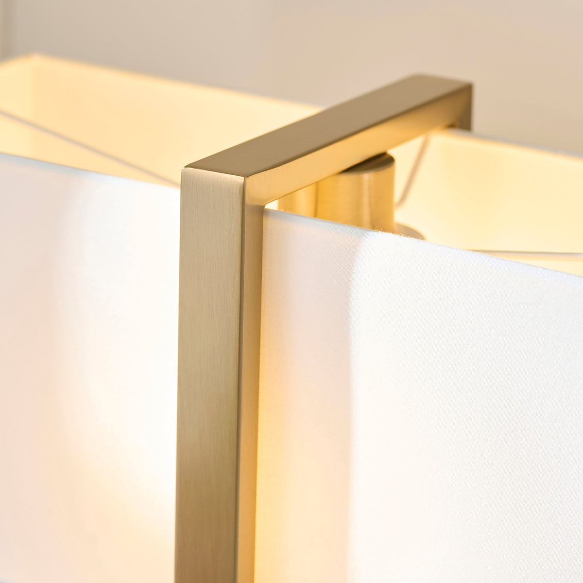 Close-up of the Seattle lamp's brushed brass frame meeting the crisp white rectangular fabric shade