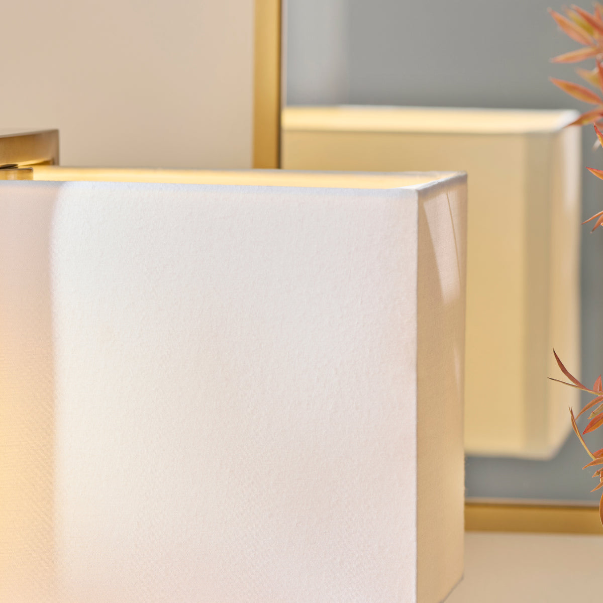 Detail of the Seattle lamp's ivory fabric shade corner with warm light spilling from the top