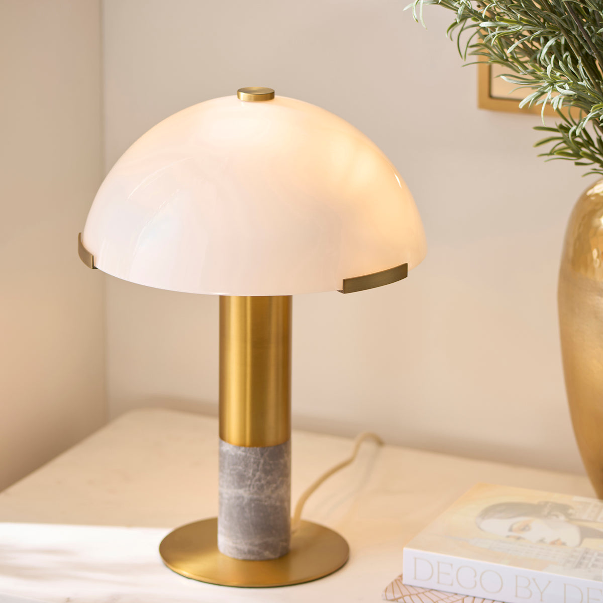 Hansel table lamp on a console, its opal dome shade casting warm light beside a mirror