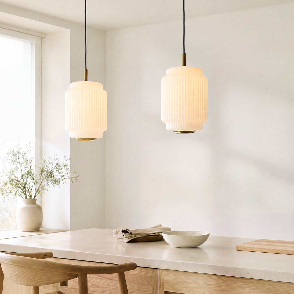 Pair of Evora cylindrical ribbed glass pendants lit above a light oak dining table