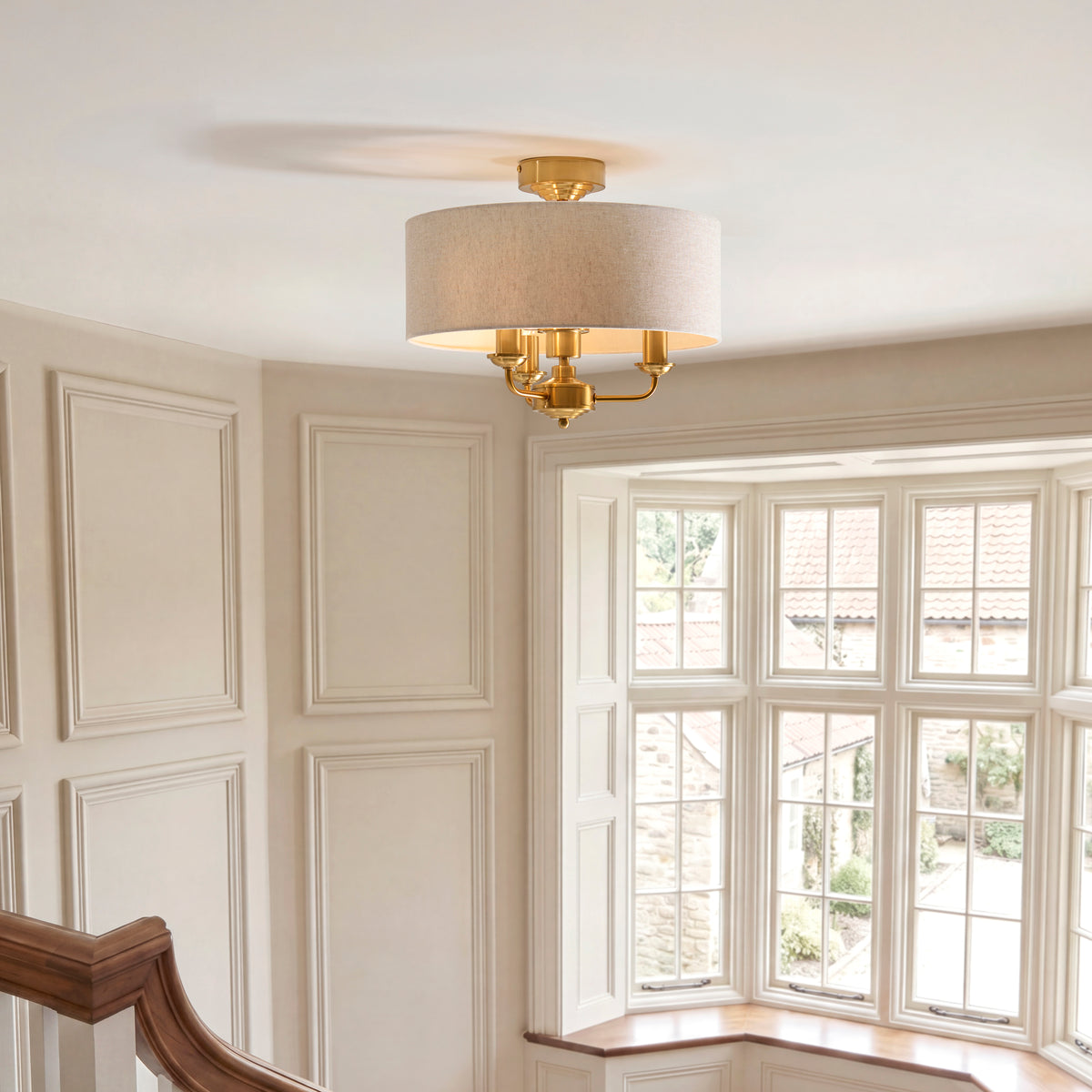 Highclere brass and linen flush light glowing on the ceiling of a cream panelled landing