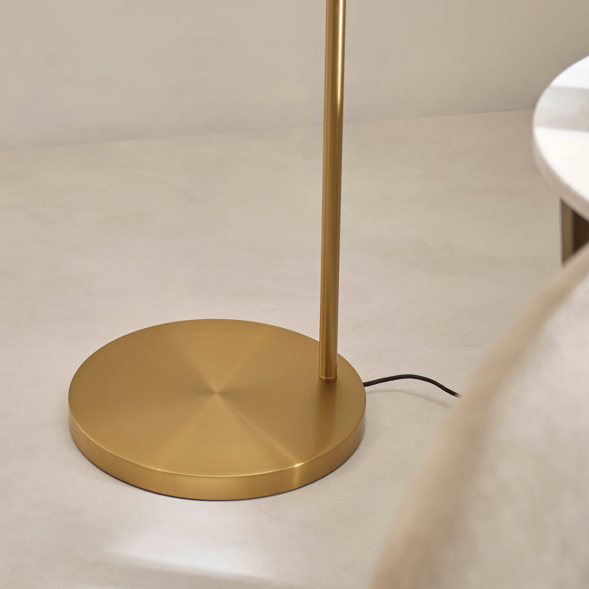 Detail of the Carlson XL floor lamp's round brushed brass base on a pale floor