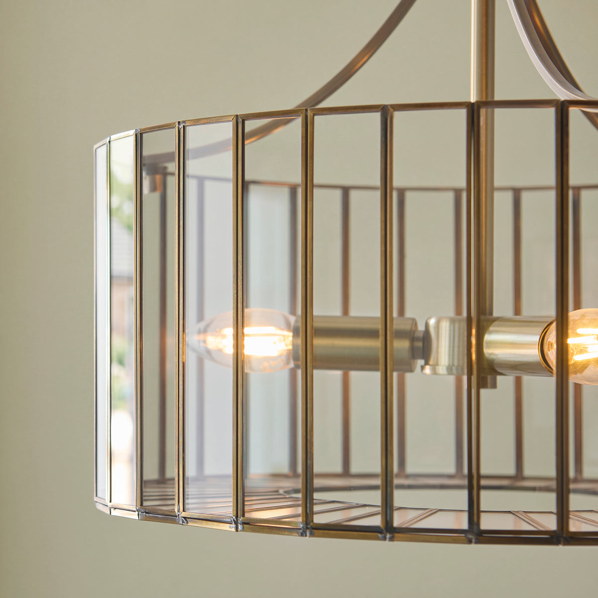 Detail of the Antalya brass slatted shade with clear glass panels and lit filament bulbs