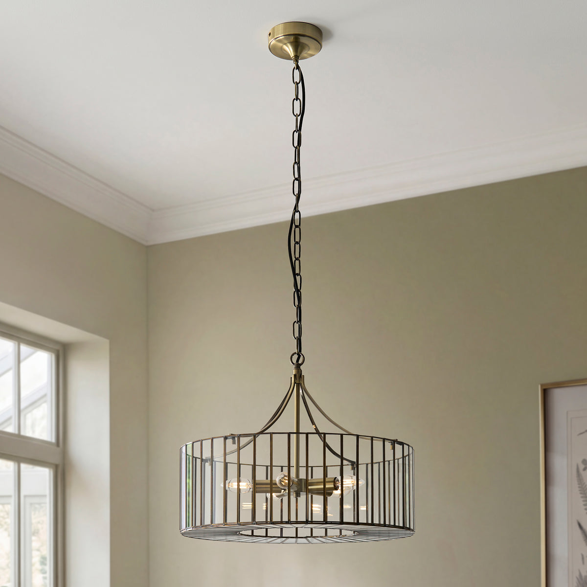 Antalya brass pendant suspended from a chain in a sage green room with cornicing