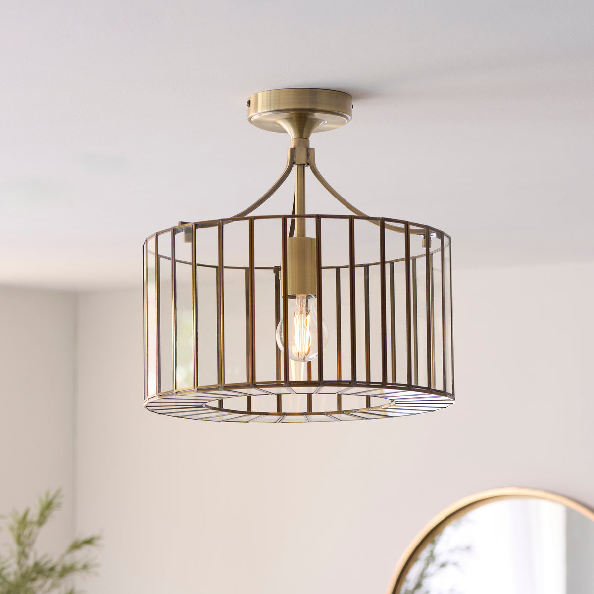 Antalya brass flush ceiling light fitted to a white ceiling above a round mirror