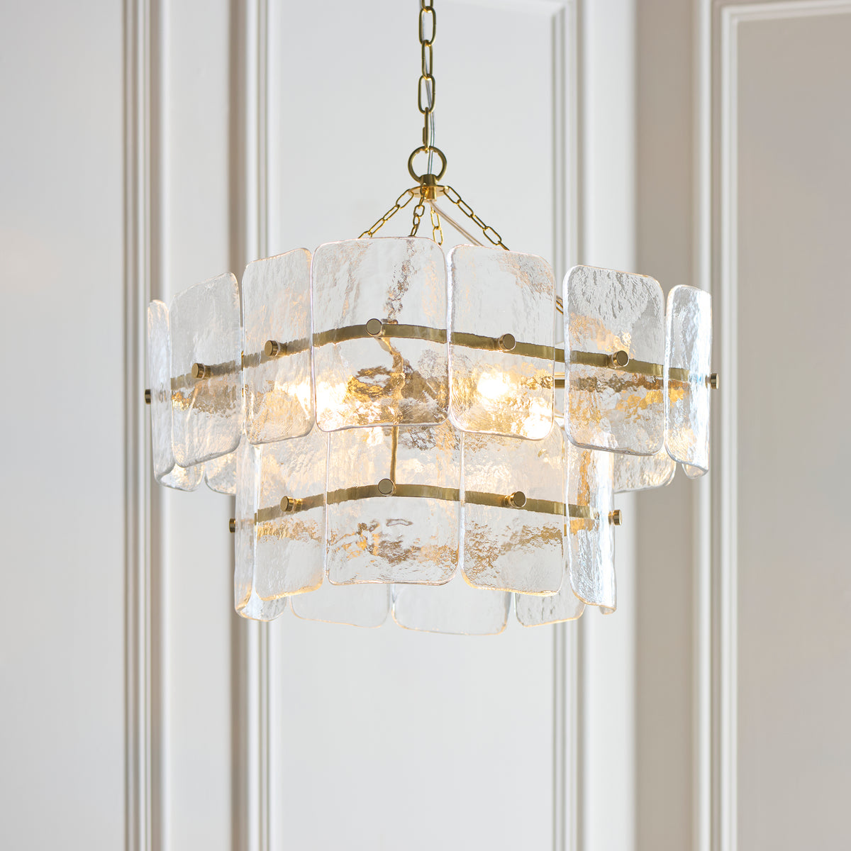 Venice pendant's tiered handmade glass panels glowing against pale wall panelling