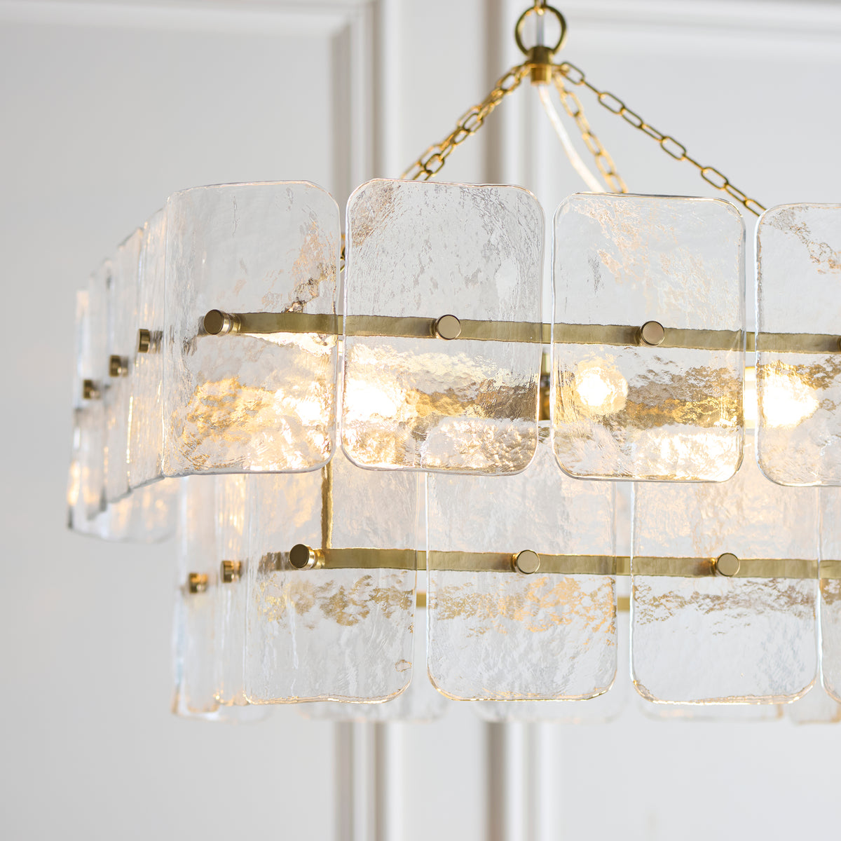 Close-up of the Venice pendant's brushed brass rails studded with textured glass tiles