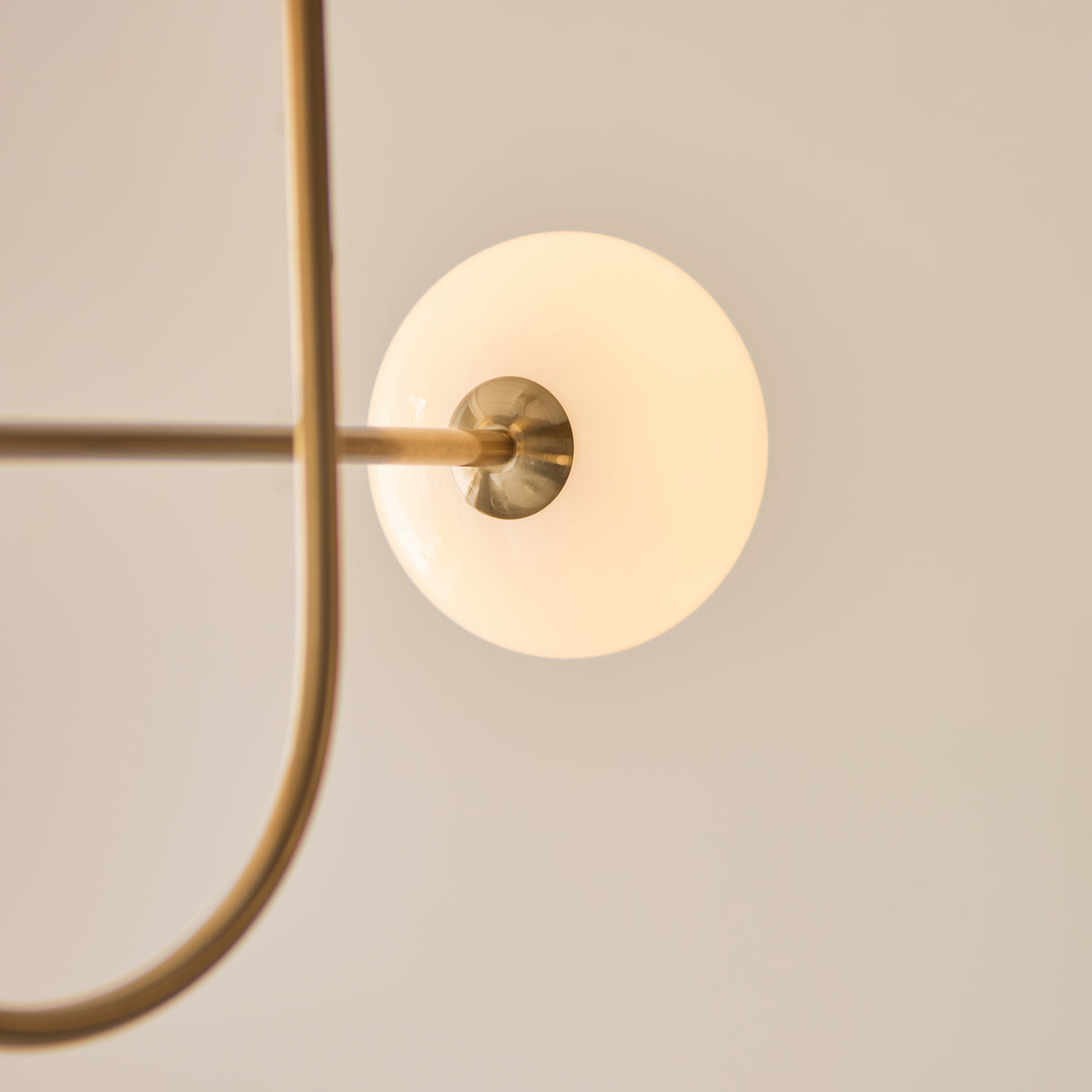 Close-up of a single round opal glass shade on the Ottowa pendant's brass arm