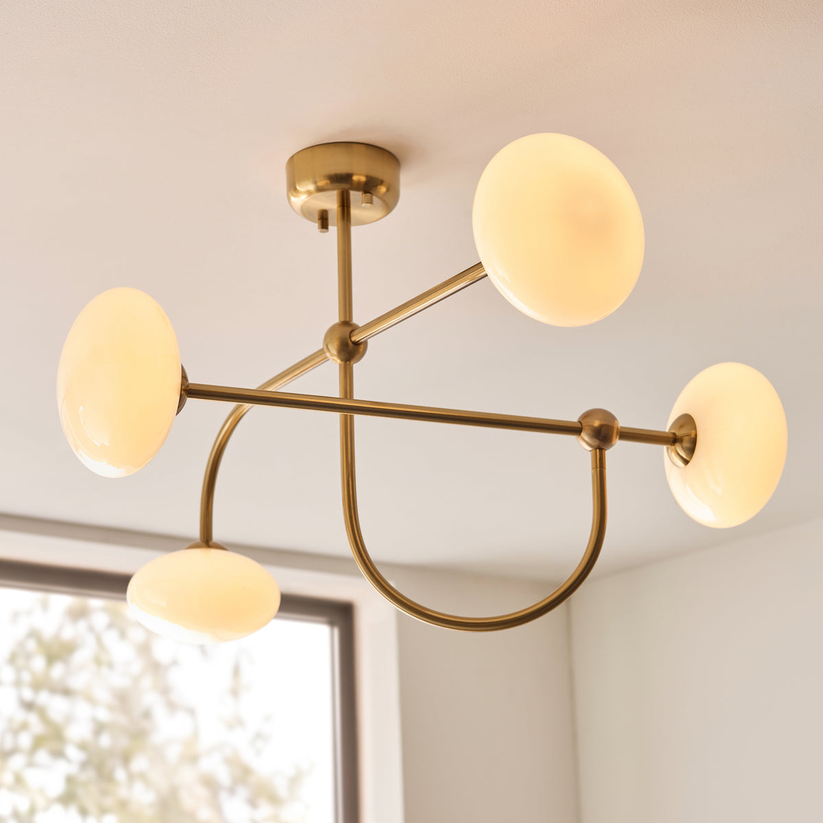 Ottowa aged brass semi flush light with opal glass shades against a sunlit white ceiling