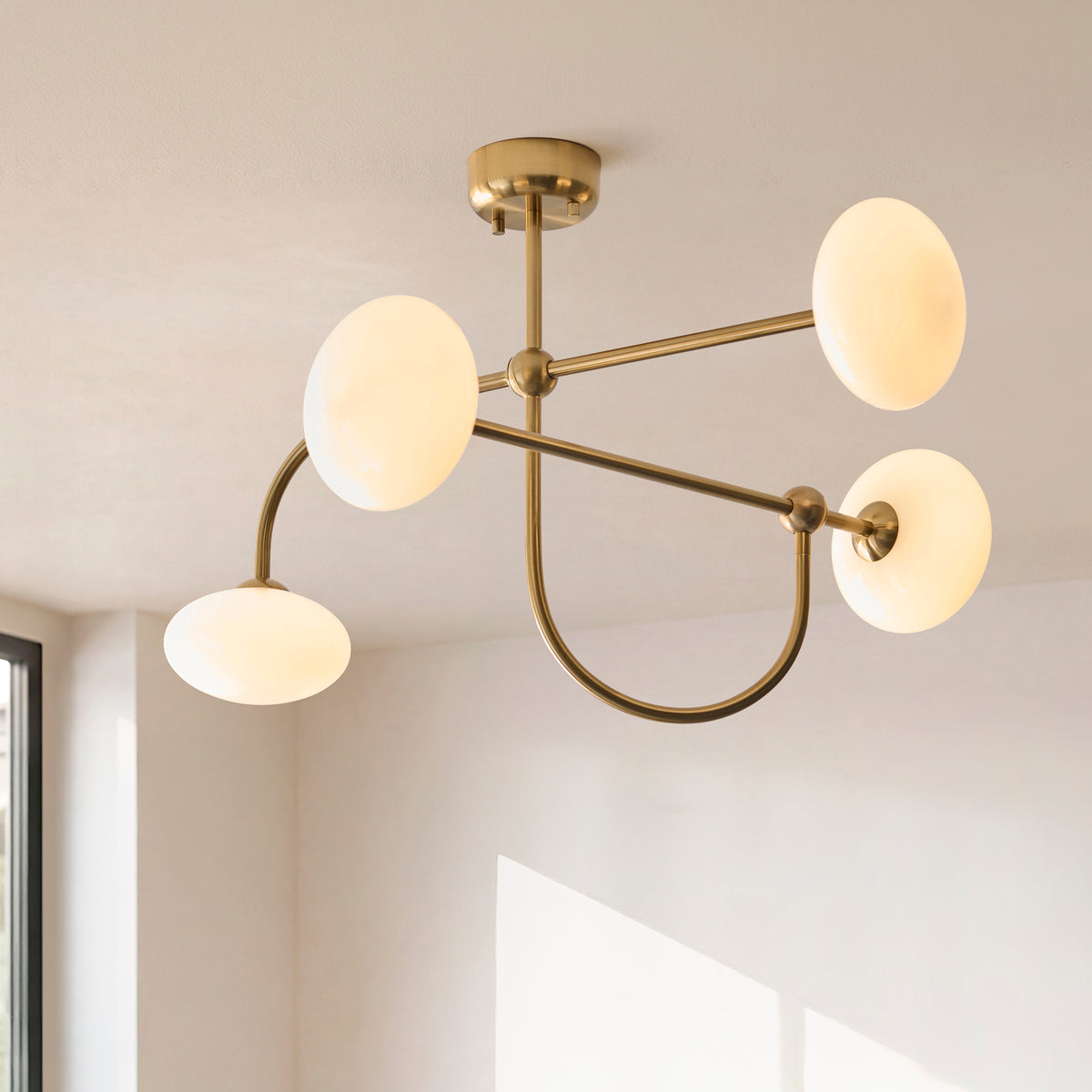 Ottowa semi flush ceiling light seen from below, brass arms sweeping between opal shades