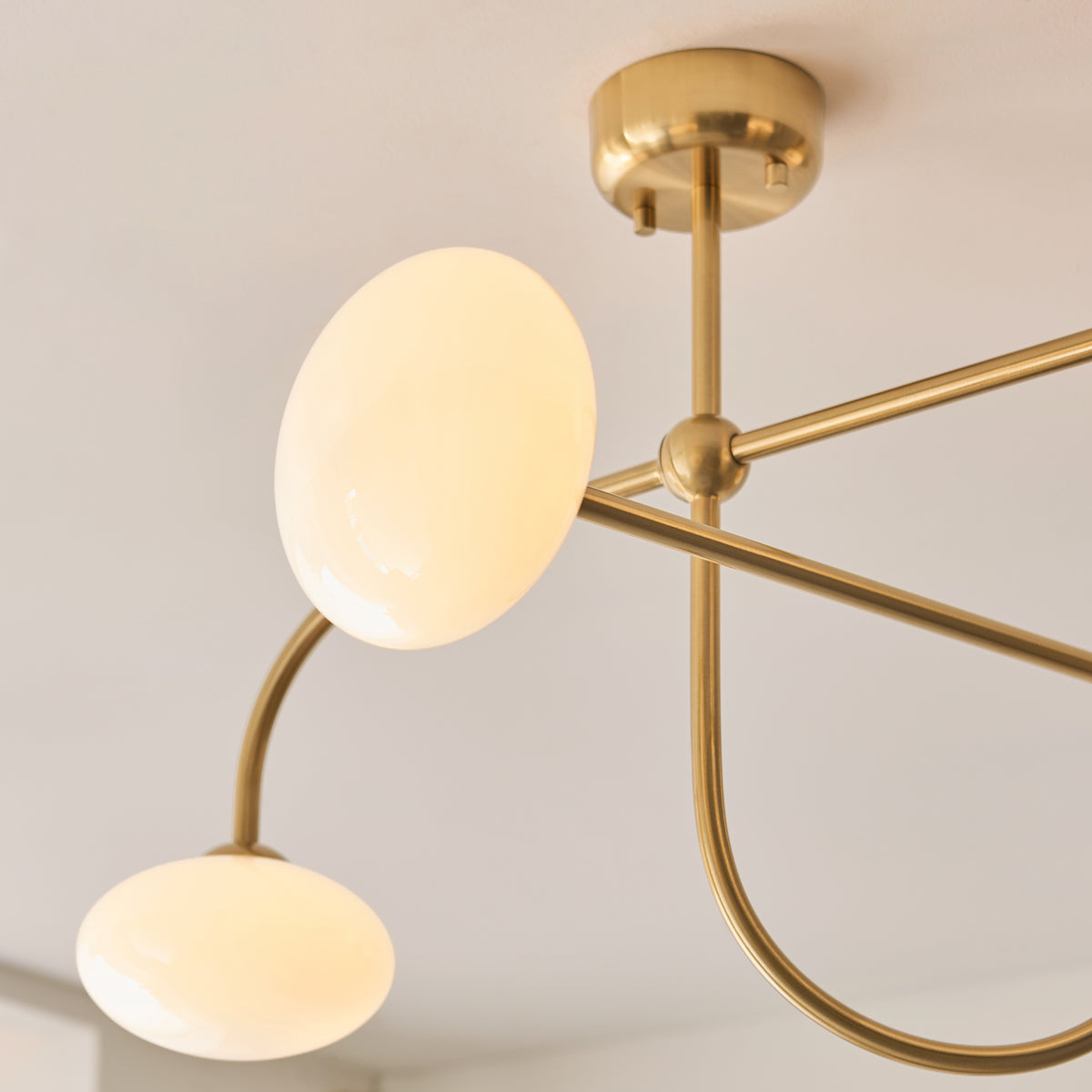 Close-up of two opal glass shades on the brass arms of the Ottowa semi flush ceiling light