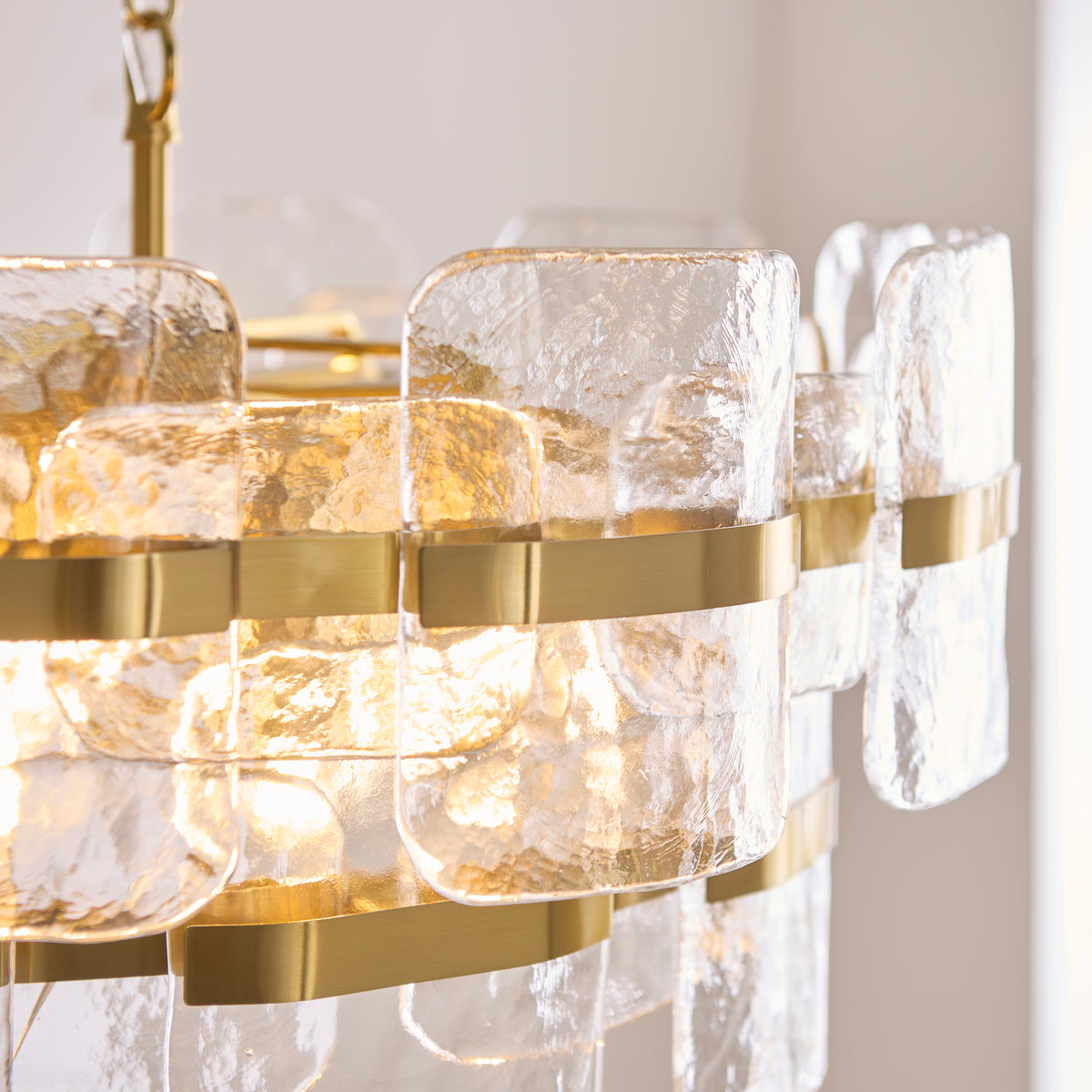 Close-up of the Ancara chandelier's mottled glass panels held by brushed brass bands