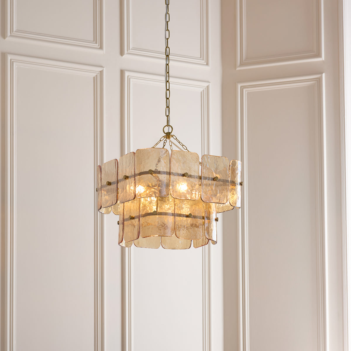 Venice aged brass chandelier glowing softly against pale panelled walls