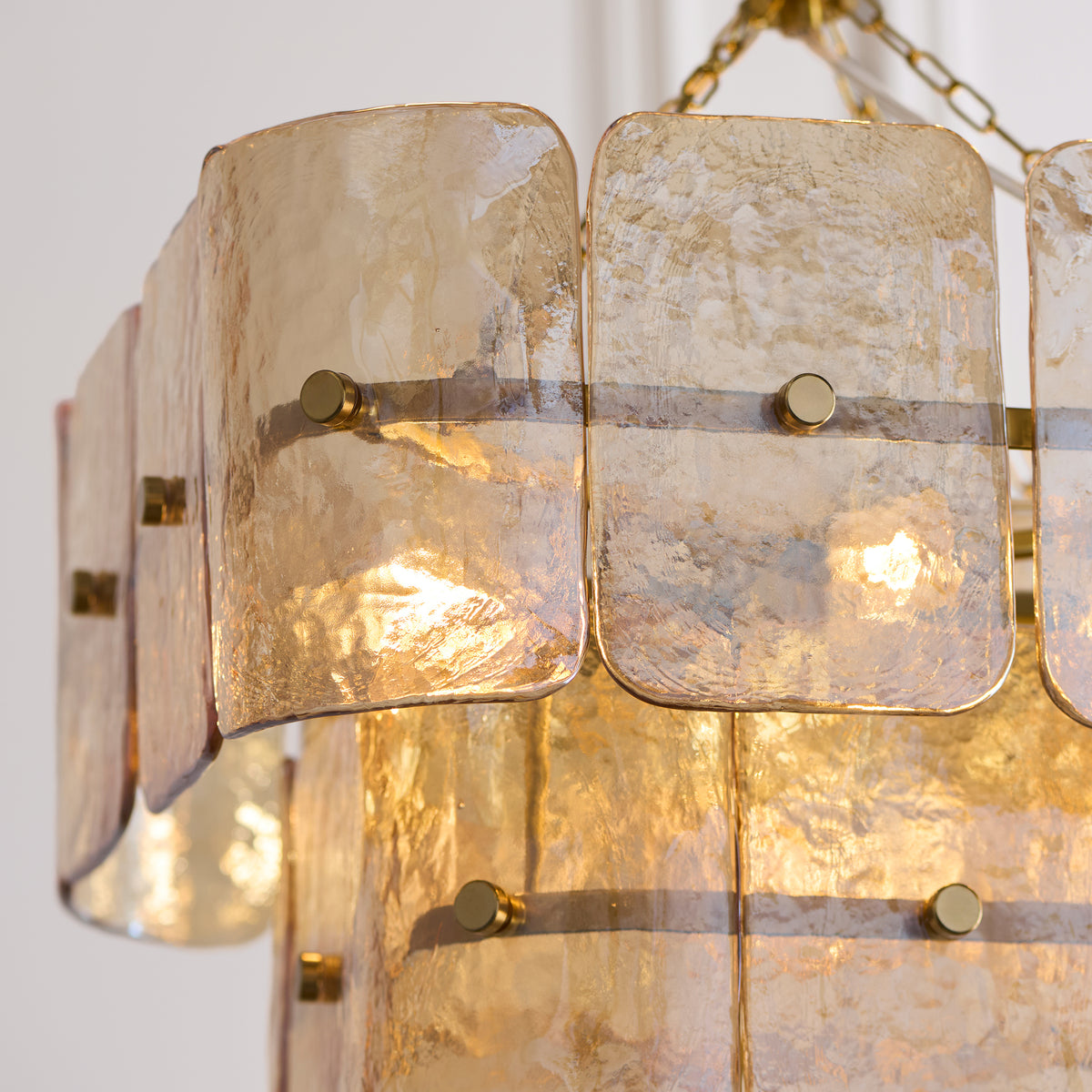 Detail of layered handmade glass panels pinned with brass studs on the Venice chandelier