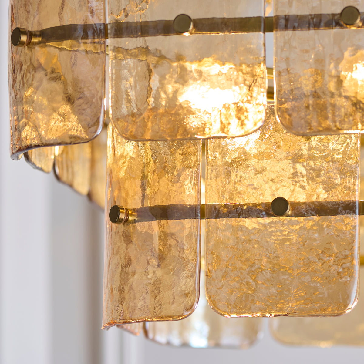 Close-up of glowing amber-toned glass panels layered across the Venice chandelier's tiers
