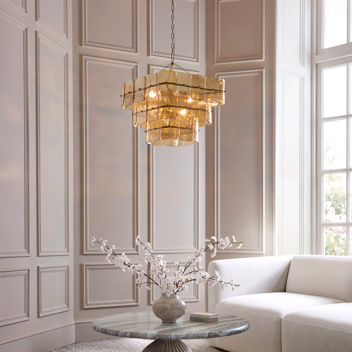 Venice champagne pendant lit above a marble table and cream sofa in a panelled living room