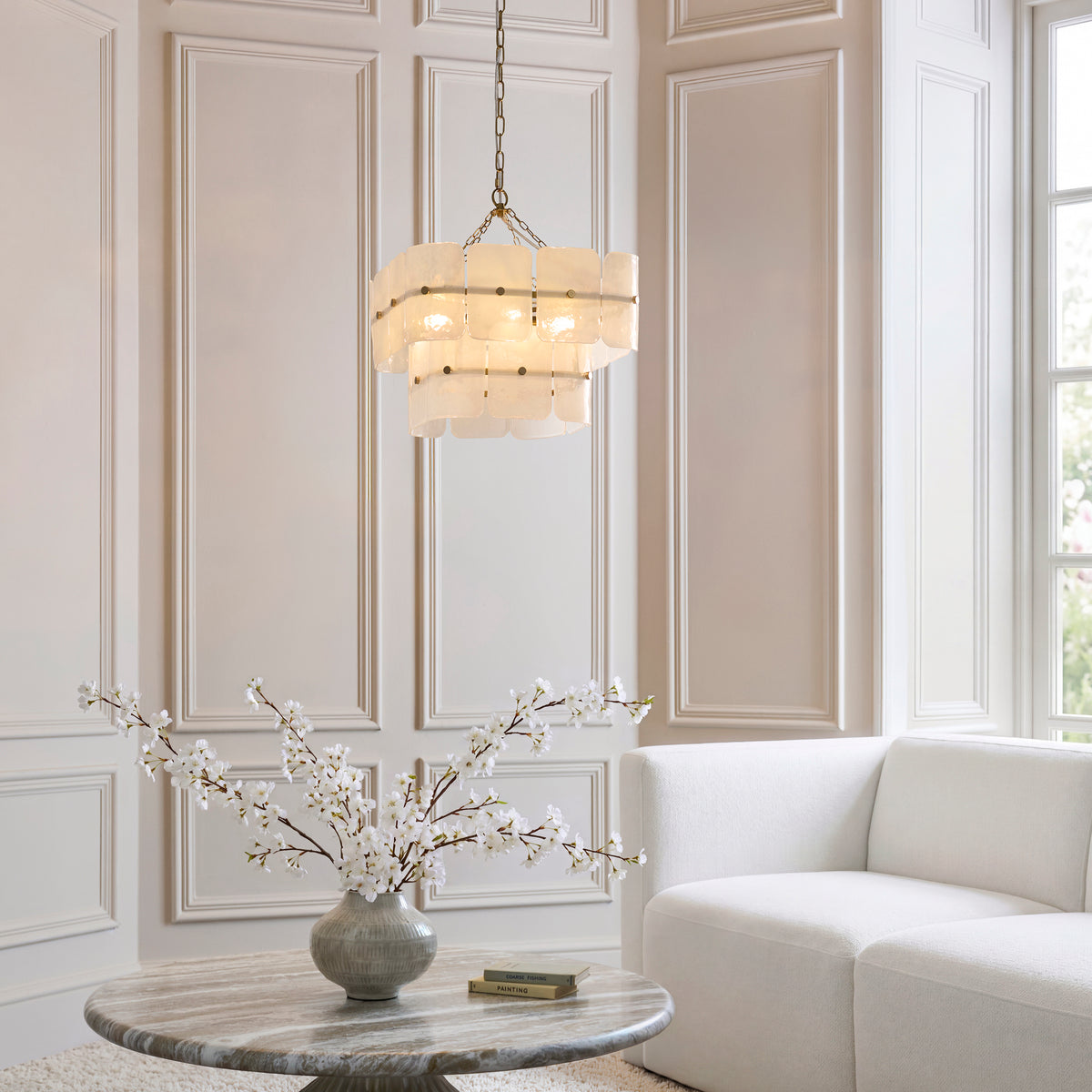 Venice glass pendant lighting a pale panelled living room with cream sofa and blossom on a stone table
