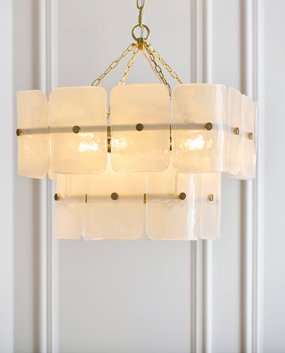 Close view of the Venice pendant's frosted textured glass panels and slim brass frame with lamps lit