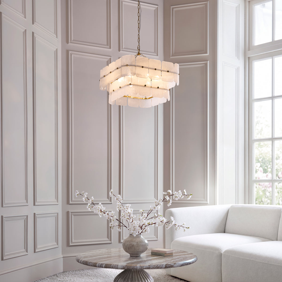 Venice 6 light chandelier lit above a marble table with cream sofa in a tall panelled living room