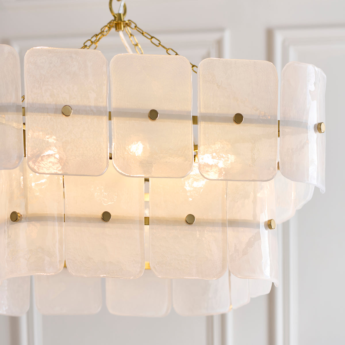 Close view of the Venice chandelier's mottled white glass tiles and brushed brass fixing studs