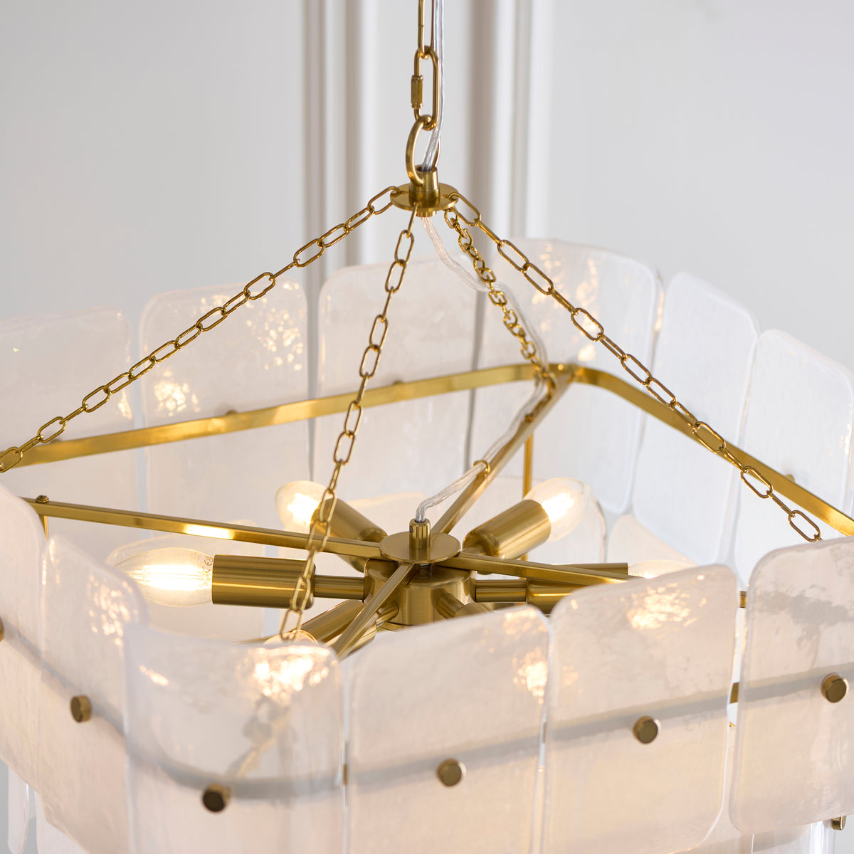 Underside of the Venice 6 light chandelier showing its brass central hub, six lamps and glass panels