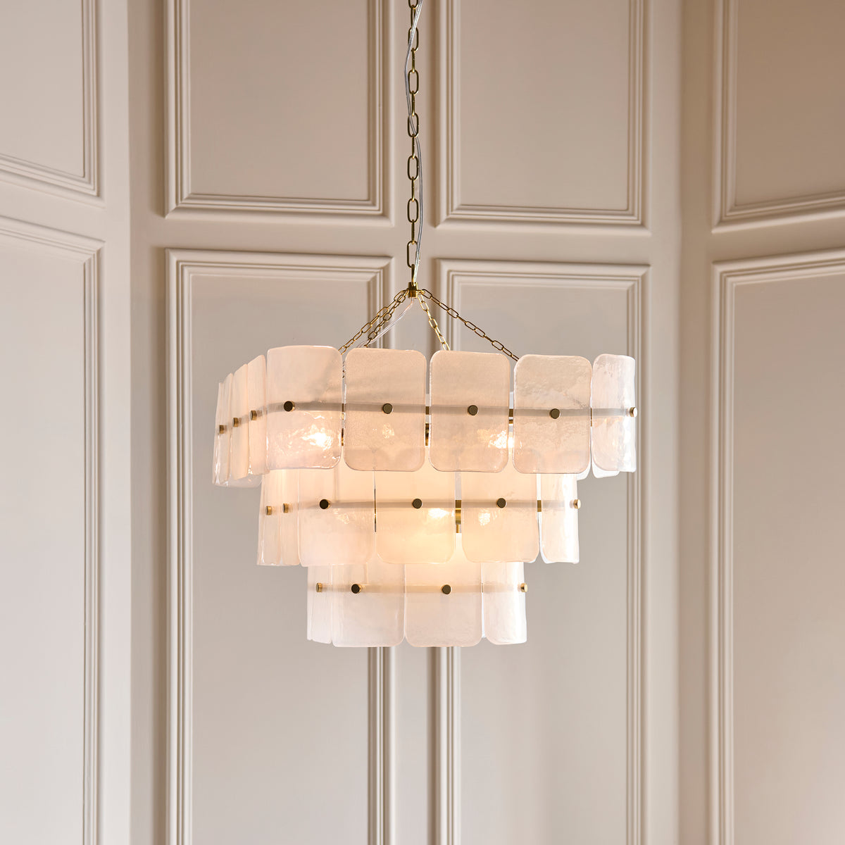 Venice 10 light chandelier hanging against panelled walls with three tiers of frosted glass panels