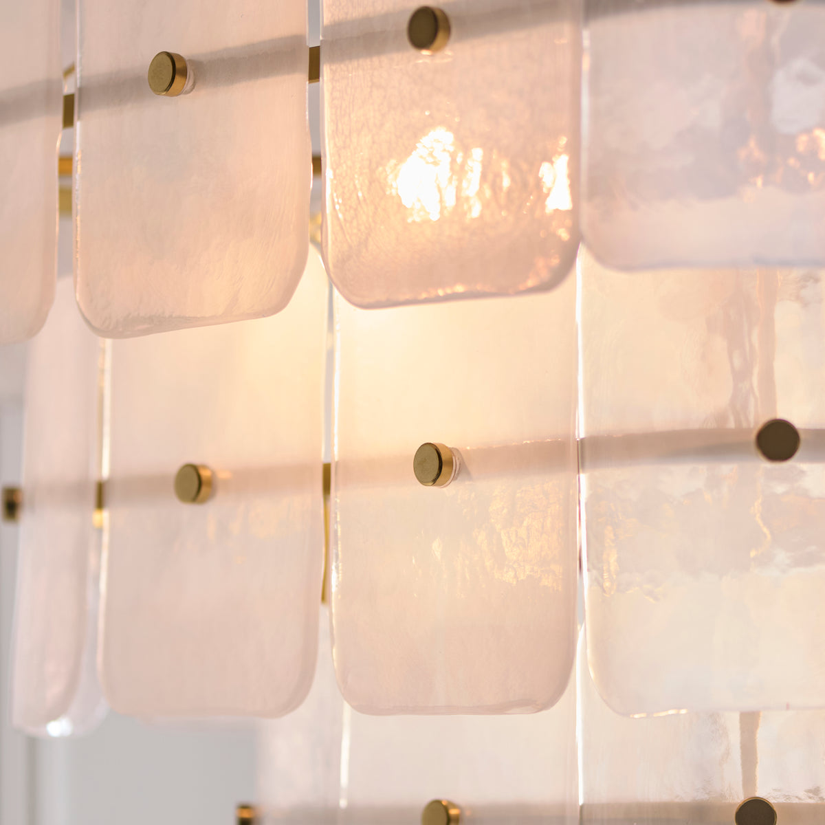 Close-up of the Venice chandelier's frosted glass tiles and brushed brass studs with warm lamp glow