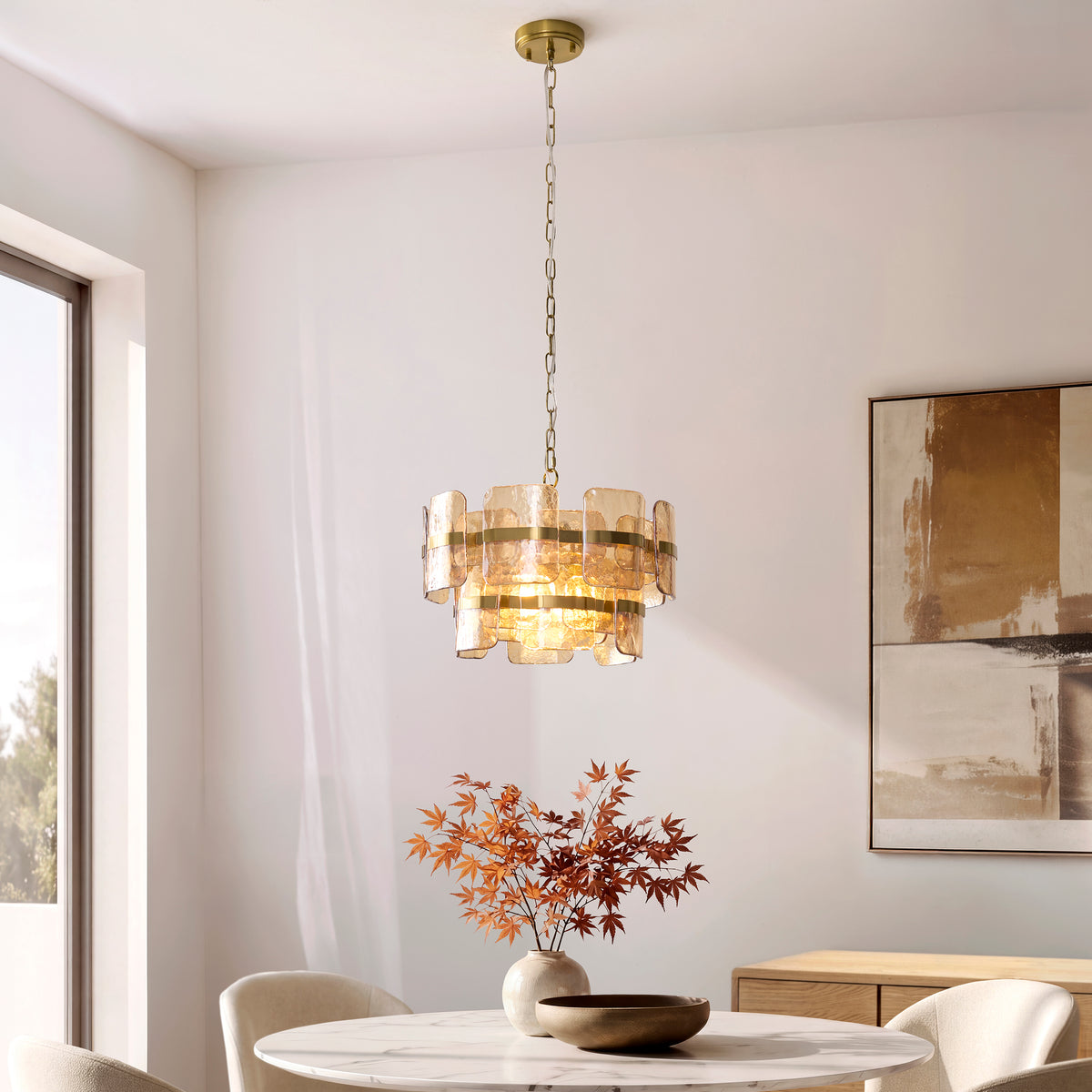 Ancara champagne glass pendant lit above a round dining table with autumn foliage and abstract art