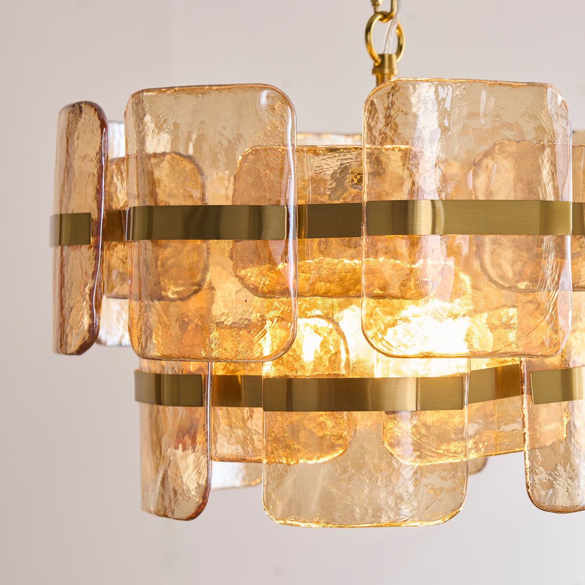 Close view of the Ancara pendant's amber-tinted textured glass panels and brass banding
