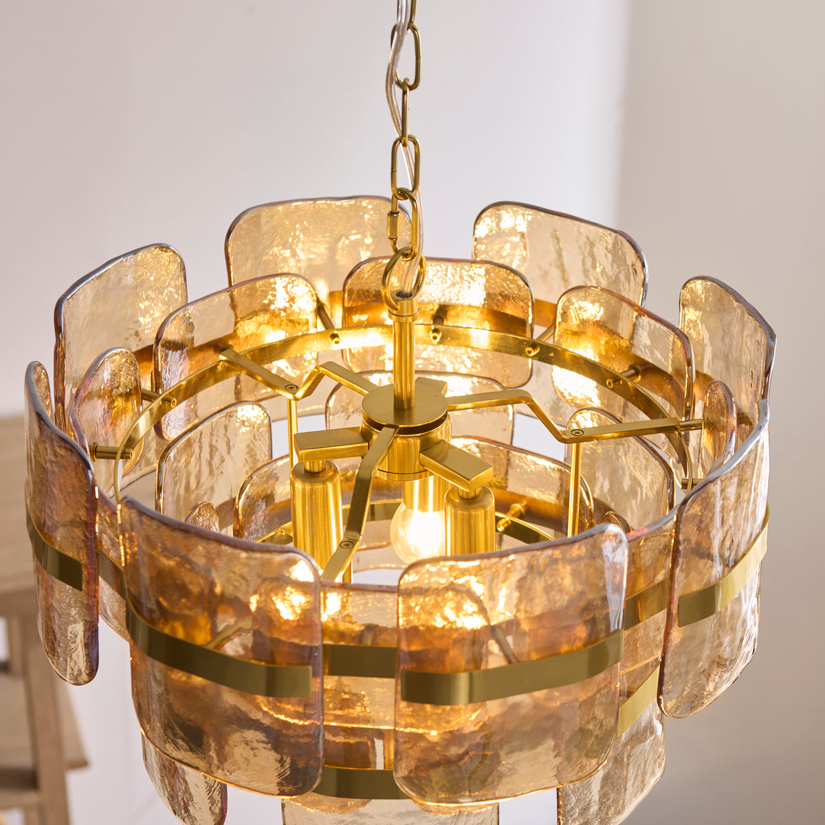 Underside of the Ancara pendant revealing the brass hub, lit lamp and champagne glass panels