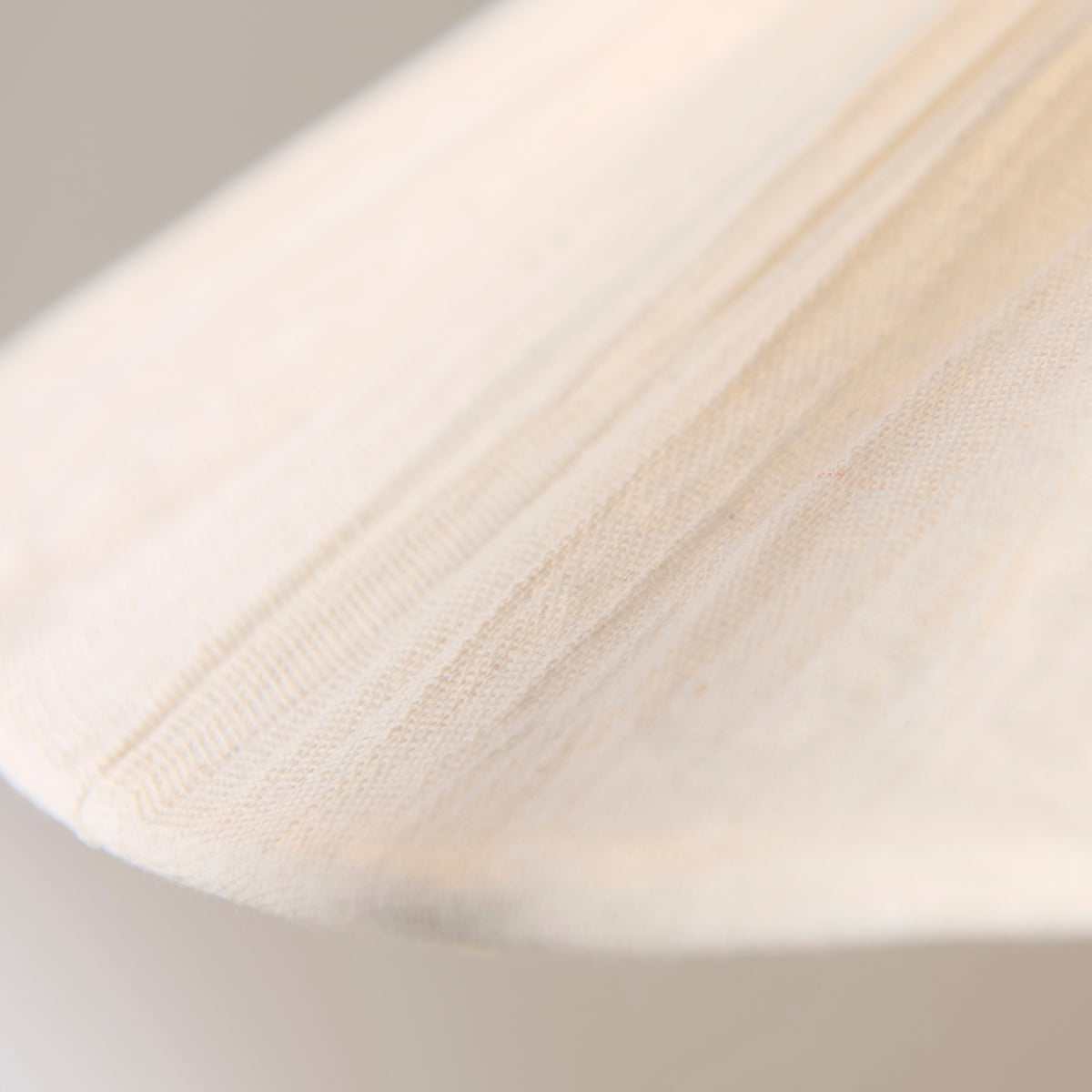 Macro detail of the cream woven fabric and stitched pleating on the Isabella Grand pendant shade