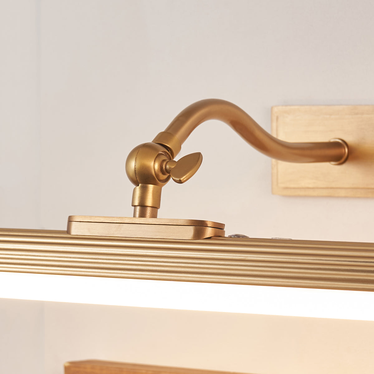 Close-up of the Kindos picture light's swan-neck arm, tilt knuckle and brass backplate