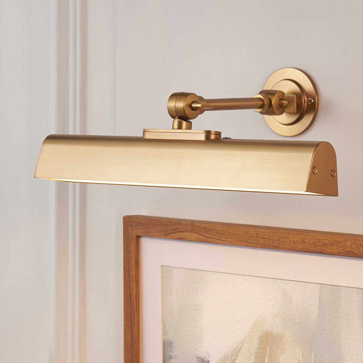 Side view of the Dalyan brass picture light and its adjustable arm above a timber picture frame