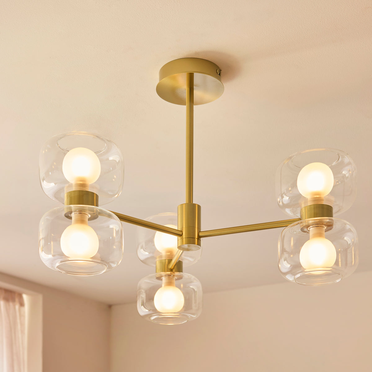 Angled view of the Rossano semi-flush light showing its brass arms and clear glass shades